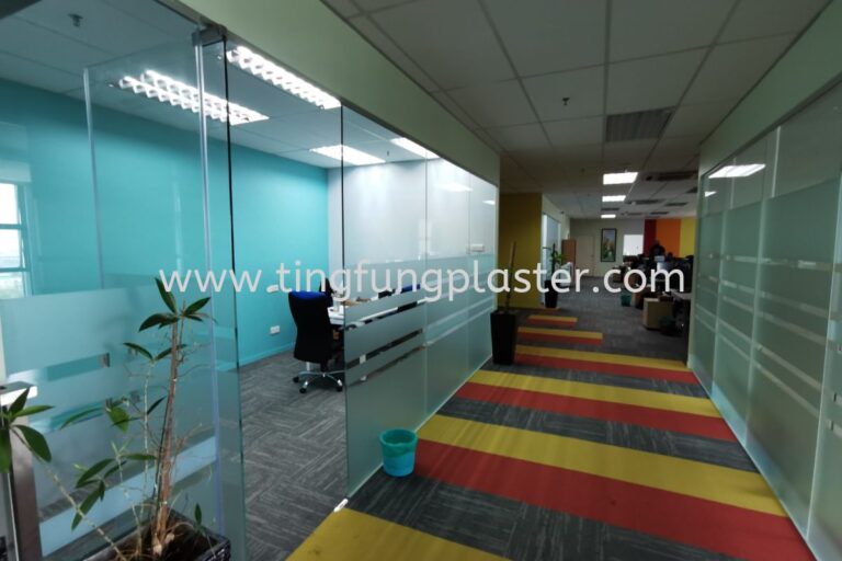 Office corridor with glass meeting rooms, striped carpet, and plants