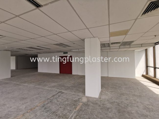Office space with suspended ceiling, white columns, and unfinished flooring during reinstatement.