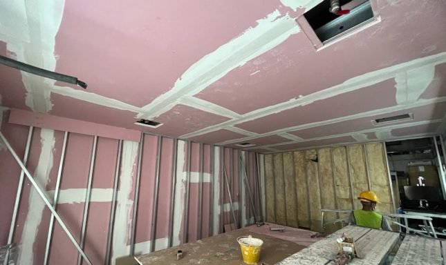 Ongoing fire-rated partition works with gypsum boards, joint compound, and site workspace setup