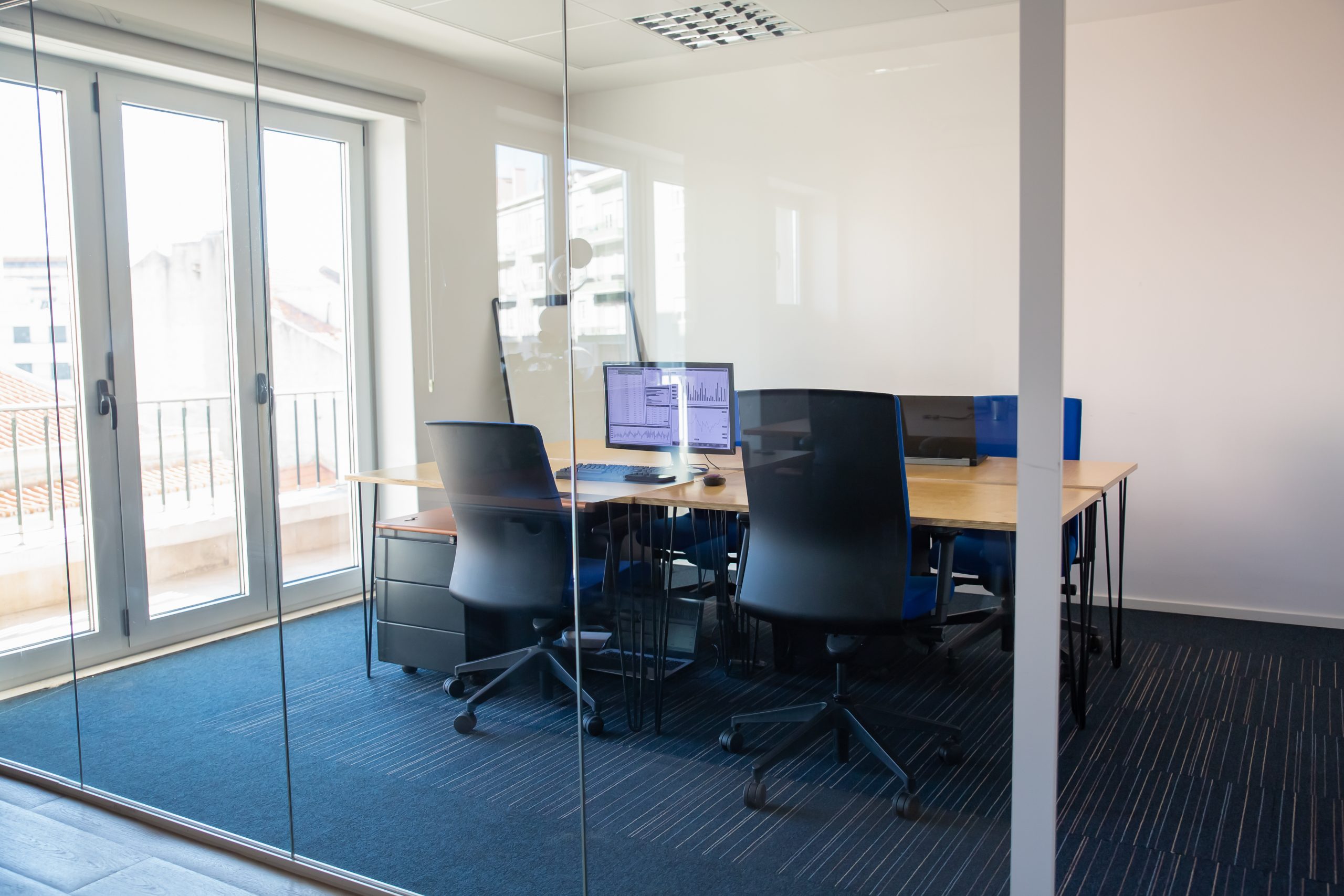 Office meeting room with glass partition walls and shared desks