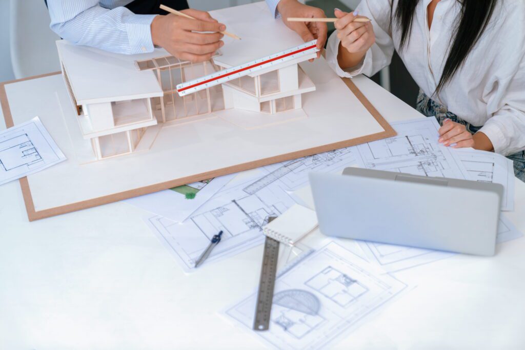 Architects reviewing building plans and measuring a model during project planning