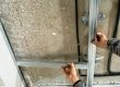 Worker installing standard drywall panels on a basic metal stud frame.