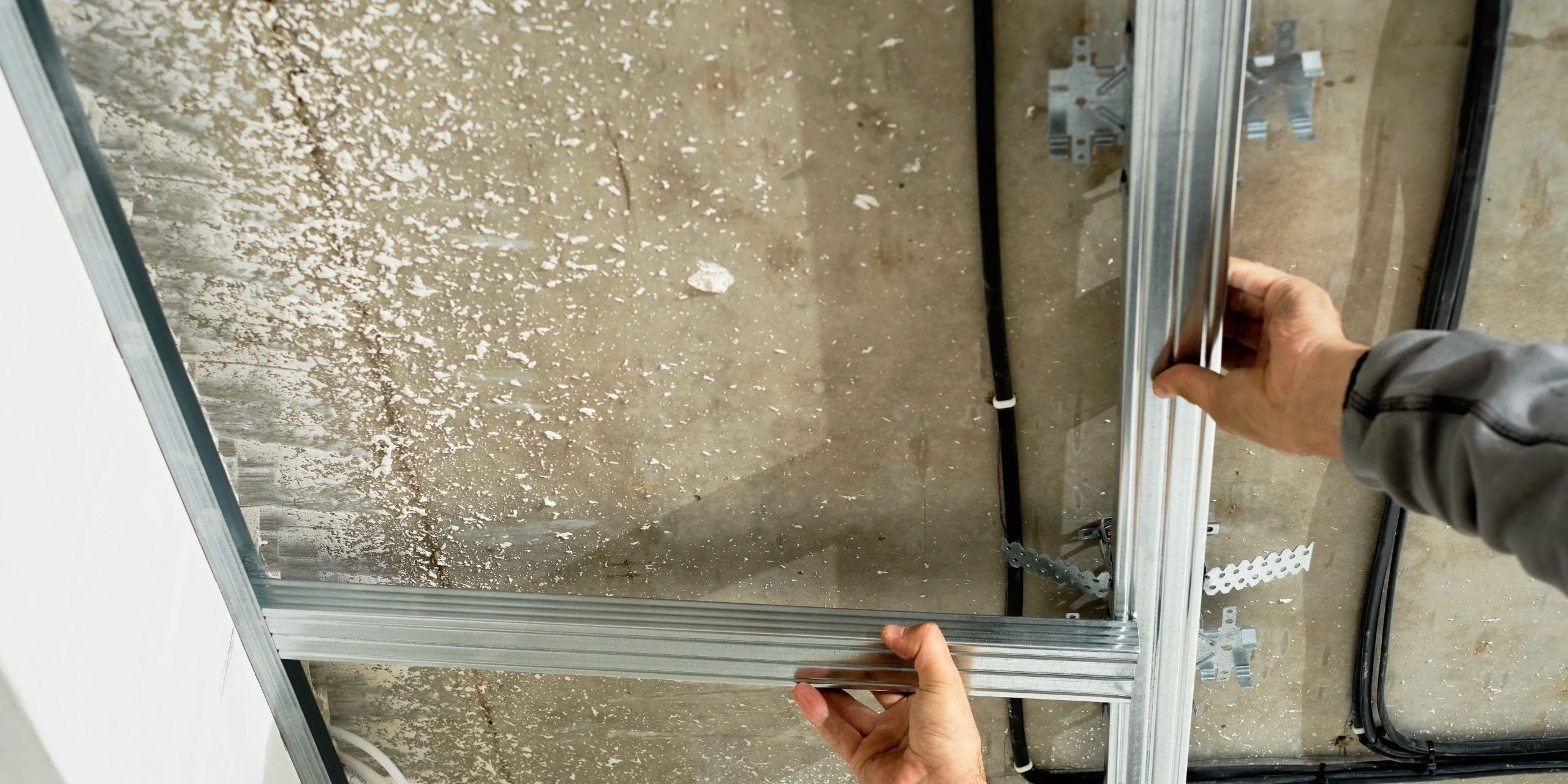 Worker installing standard drywall panels on a basic metal stud frame.