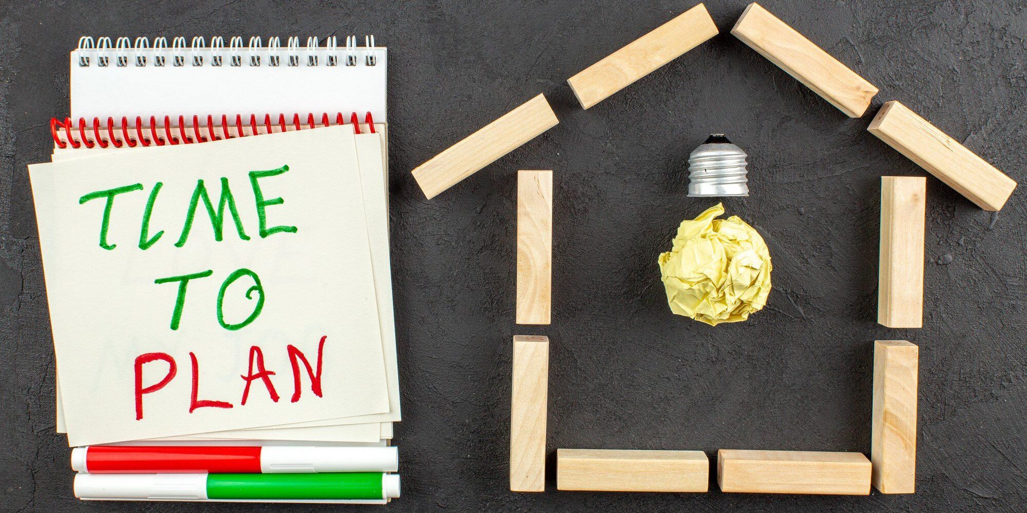 top view idea light bulb house shaped wood blocks time plan written notepad red green markers black